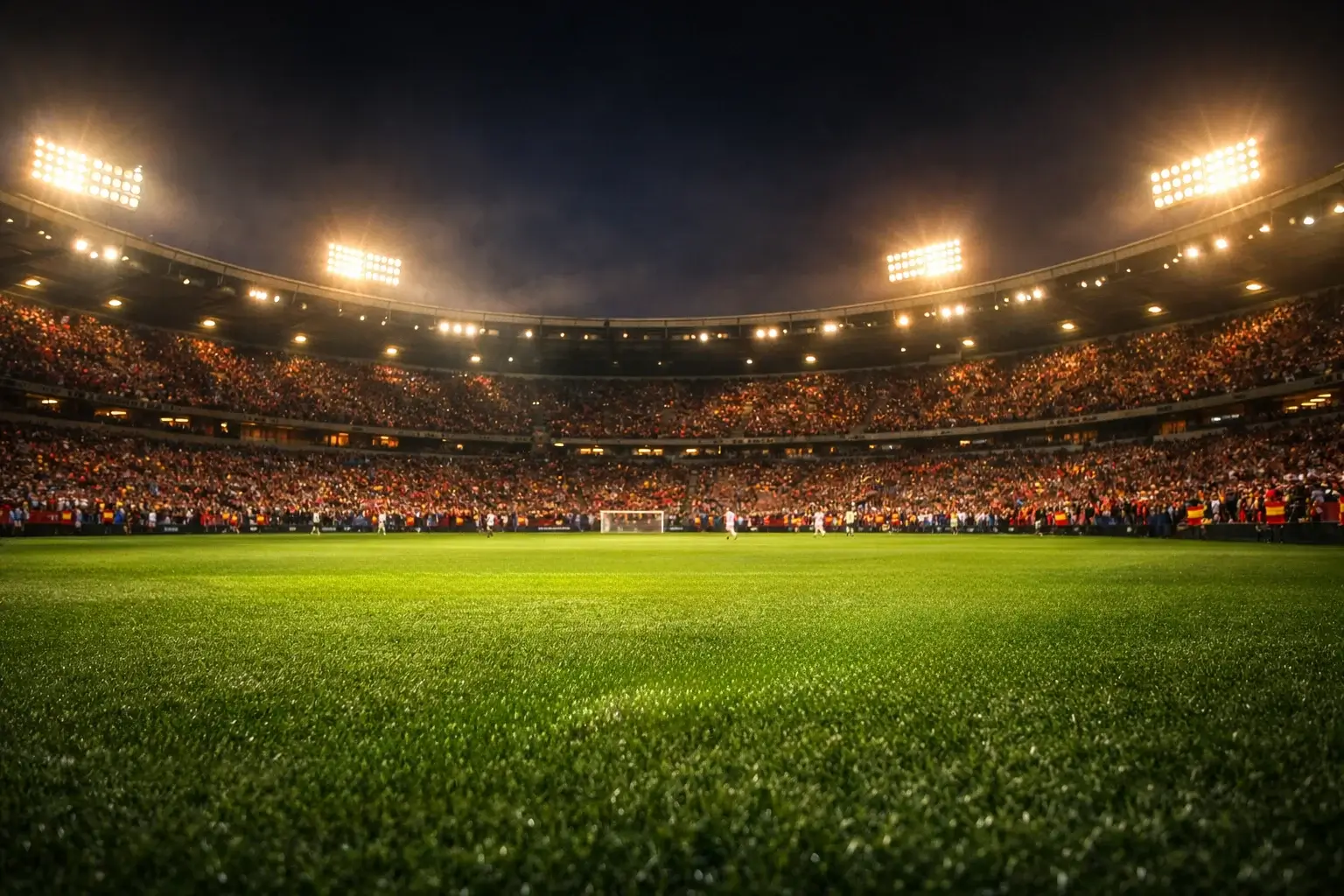 Estadio de fútbol iluminado durante un partido nocturno con aficionados en las gradas